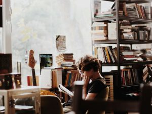 woman reading book sitting beside electronic keyboard